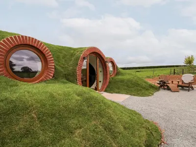 a small house on a grassy hill with a round window at Shire's End in Caynham