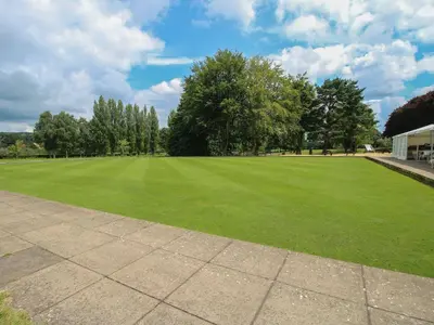 a large green field with trees and a building at Dove in Leominster