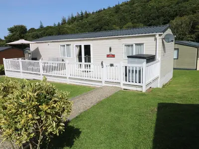 a white house with a white fence and a yard at 116 Woodpecker Lodge in New Quay