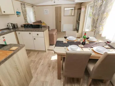 a kitchen and living room with a table and chairs at 116 Woodpecker Lodge in New Quay