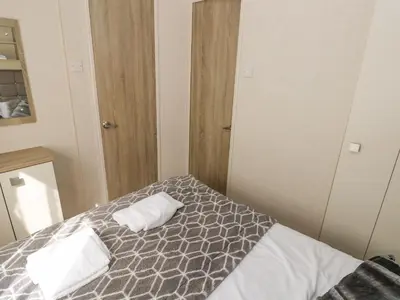 a bedroom with a bed with two towels on it at 116 Woodpecker Lodge in New Quay