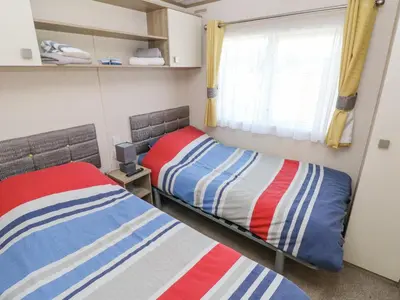 a bedroom with two beds and a window at 116 Woodpecker Lodge in New Quay