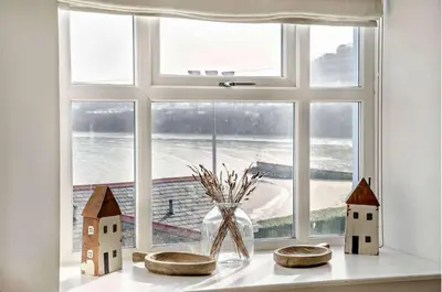 a window with a vase and houses in front of it at No.1 Sail House in New Quay