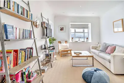 a living room with a couch and a book shelf with books at No.1 Sail House in New Quay