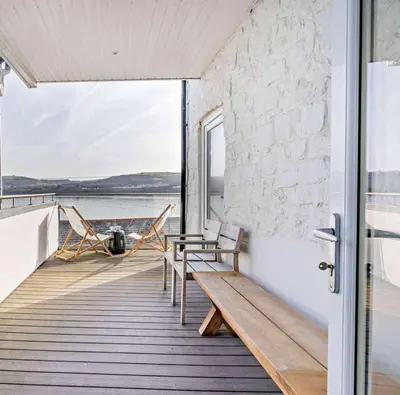 a porch with two chairs and a bench on a house at No.1 Sail House in New Quay