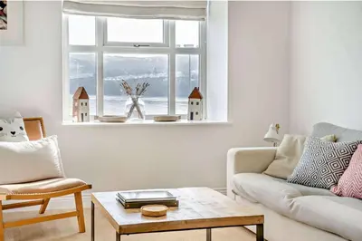 a living room with a couch and a table and a window at No.1 Sail House in New Quay