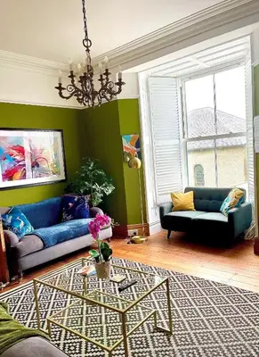 a living room with two blue couches and a table at Rhianfa 4 bedroom house minutes walk from the beach in New Quay