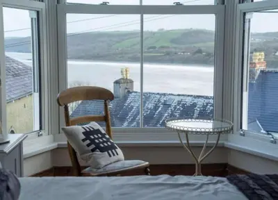 a bedroom with a bed and a table and a window at Rhianfa 4 bedroom house minutes walk from the beach in New Quay