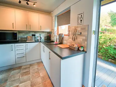 a kitchen with white cabinets and a large window at Arenig - Bala Lake in Bala