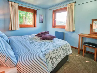a blue bedroom with a bed and a desk and windows at Arenig - Bala Lake in Bala