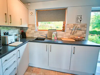 a kitchen with white cabinets and a sink and a window at Arenig - Bala Lake in Bala