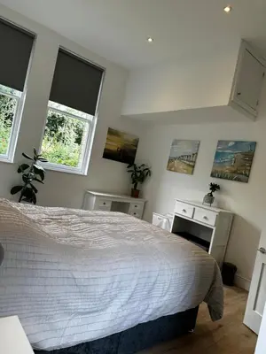 a bedroom with a bed and two windows at Flat 2 The Butlers Quarters in Oswestry