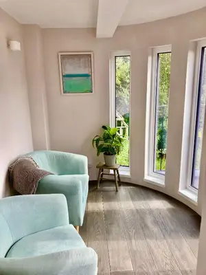 a living room with two chairs and two windows at The Old Stables, The River Severn, Shrewsbury in Shrewsbury