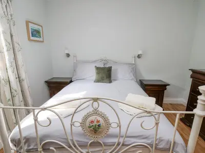 a bedroom with a white bed with white sheets at The Coach House at Plas Dolguog in Machynlleth
