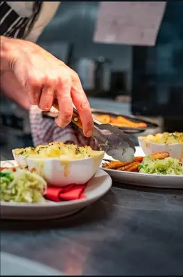 a person is serving food from plates of food at The Cock Hotel in Bronllys
