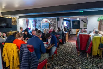 a group of people sitting at tables in a restaurant at The Cock Hotel in Bronllys