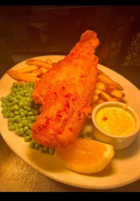 a plate of food with fish and chips and peas at The Cock Hotel in Bronllys