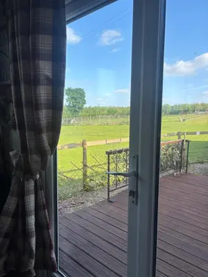 a sliding glass door with a view of a field at Bridie -rose with wood tub country retreat in Kington