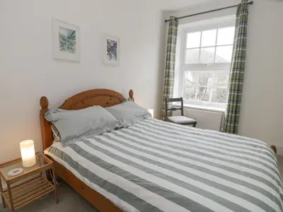a bedroom with a bed with a striped comforter and a window at Swn Yr Afon in Tywyn
