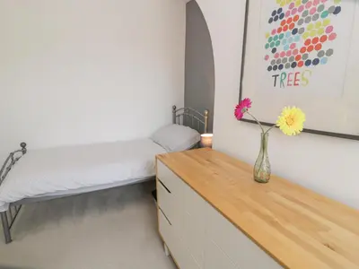 a bedroom with a bed and a vase with flowers on a dresser at Swn Yr Afon in Tywyn