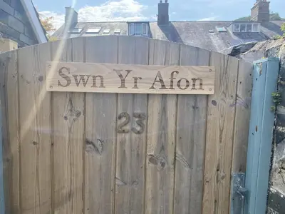 a wooden fence with a sign that reads swim iv infusion at Swn Yr Afon in Tywyn