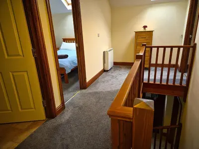 a hallway with a room with a bed and a staircase at Peregrine Stable Cottage in Llandovery
