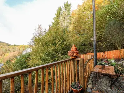 a wooden deck with a table and a fence at The Kites Nest in Ystrad Meurig
