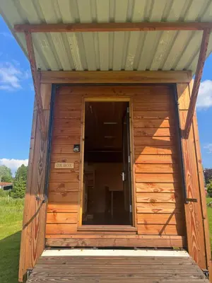 a wooden outhouse with a glass door in a field at Ox Box Cabin Lyonshall Kington in Hereford