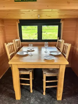 a wooden table with four chairs and wine glasses at Beaver Tail Cabin in Hereford
