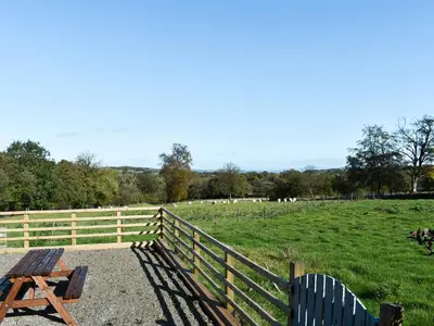 a picnic table and chairs in front of a field at Cartws Blaenparc Coach House - Uk41031 in Mydroilin