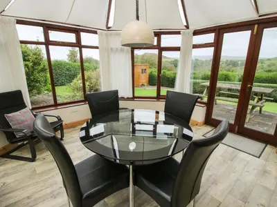 a dining room with a glass table and black chairs at Rowan Cottage in Shrewsbury