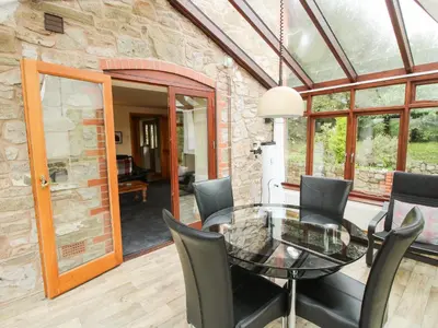 a dining room with a glass table and chairs at Rowan Cottage in Shrewsbury