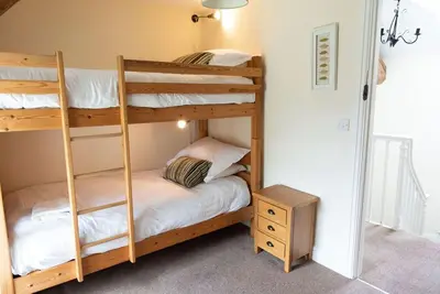 a bunk bed room with two bunk beds and a table at Penuwch Fach in Aberystwyth