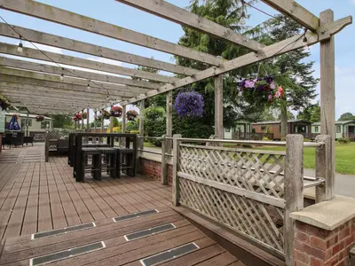 a wooden pergola with a table and benches on a deck at Mallard in Leominster