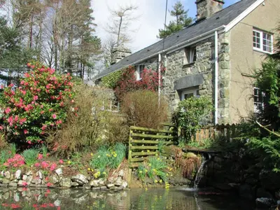 a stone house with a pond in front of it at Bryn Sion Farm in Dinas Mawddwy