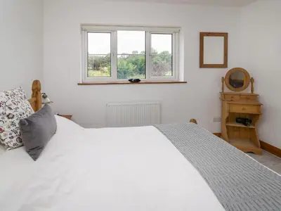 a bedroom with a white bed and a window at Rhydygroes in Lampeter