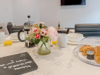 a table with a vase of flowers and pastries on it at 5A One Bedroom Modern Town Centre Apartment - Pass the Keys in Shrewsbury