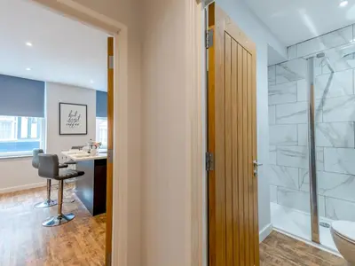 a bathroom with a shower and a desk with a chair at 5A One Bedroom Modern Town Centre Apartment - Pass the Keys in Shrewsbury