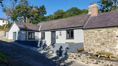 a stone house with a bench in front of it at No 1 Dolheulog Aberaeron SA46 0EP in Aberaeron