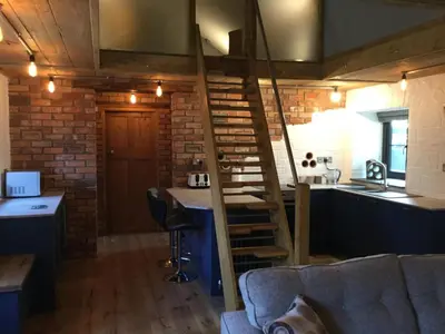 a living room with a staircase and a kitchen at No 1 Dolheulog Aberaeron SA46 0EP in Aberaeron