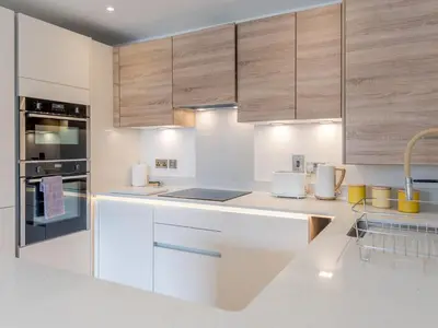 a kitchen with white counter tops and wooden cabinets at 1 bed Albury Contemporary Apartment with Secure Parking - Pass the Keys in Shrewsbury