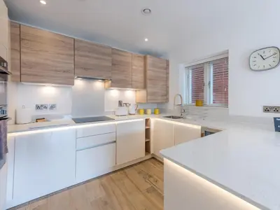 a kitchen with white cabinets and a clock on the wall at 1 bed Albury Contemporary Apartment with Secure Parking - Pass the Keys in Shrewsbury