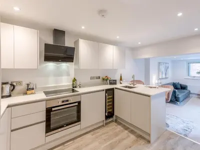 a kitchen with white cabinets and a living room at Bouvardia Modern town centre apartment - Pass the Keys in Shrewsbury