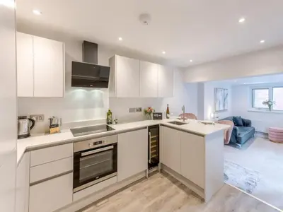 a kitchen with white cabinets and a living room at Bouvardia Modern town centre apartment - Pass the Keys in Shrewsbury