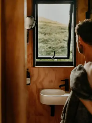 a man looking out the window of a bathroom with a sink at Hoku in Llangollen
