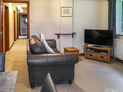 a living room with a leather couch and a television at Cysgod Y Coed in Llanbedr