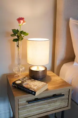 a table with a lamp and a book and a flower at Shrewsbury Townhouse - Free Parking in Shrewsbury
