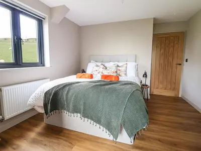 a bedroom with a bed with a green blanket on it at Mynydd Y Glyn Lodge in Llanfyllin