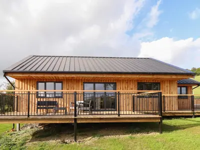 a log cabin with a deck and a house at Mynydd Y Glyn Lodge in Llanfyllin