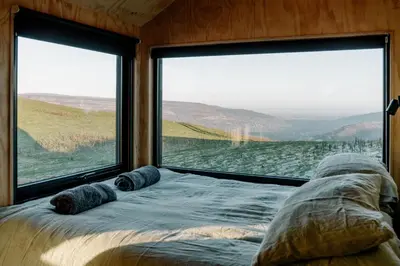 a bed in a room with a large window at Vega in Llangollen